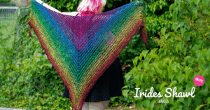 Frau mit bunten Haaren hält ein Regenbogenfarbenes Tuch mit ihren ausgestreckten Armen an ihrem Rücken.